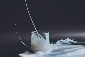 A small glass with milk being poured in 
